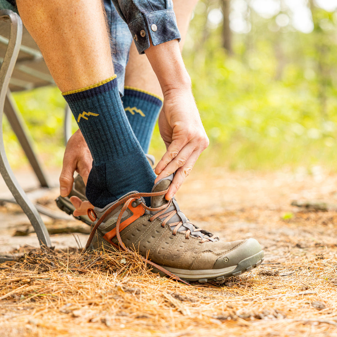 model putting on hiking shoes while wearing the 1466 Micro crew midweight hiker in dark teal
