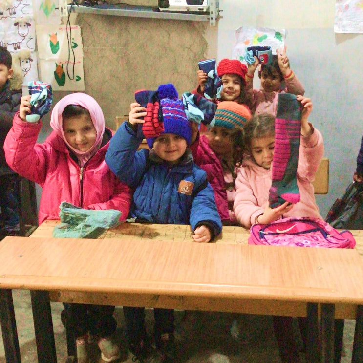 Orphans holding up new pairs of Darn Tough socks